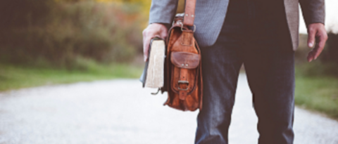 [Translate to Englisch:] Mann mit Schultertasche und Buch